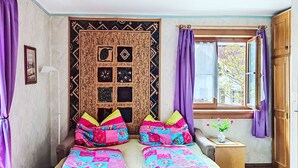 A room with a bed, a window with curtains, a wall tapestry, and a small table with a vase. - Wieshammer by Interhome (Niedernsill)