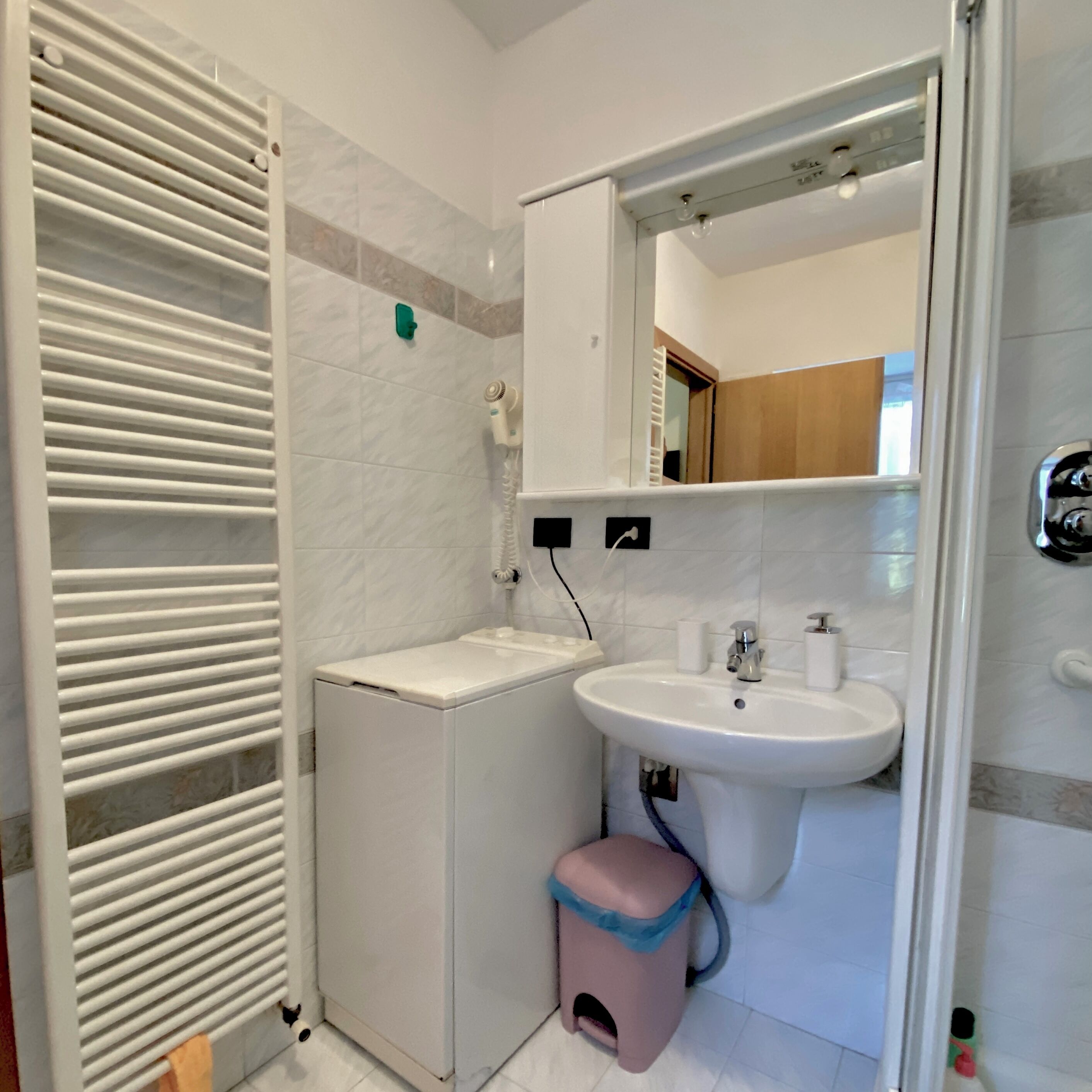 Ein kleines Badezimmer mit einem weißen Waschbecken, Spiegel und Handtuchhalter.