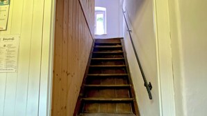 A wooden staircase with a handrail, leading to a room with a window.
