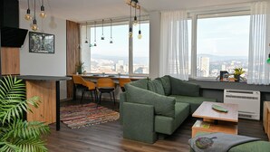 Un salon moderne avec un canapé vert, une table basse en bois et un coin repas comprenant une table et des chaises en bois.