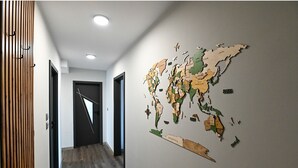Un couloir orné d’une fresque représentant une carte du monde sur un mur, avec des lambris en bois sur le côté gauche et une porte au fond.