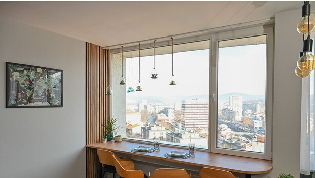 Un espace repas doté d’une grande fenêtre, de lambris en bois, de luminaires suspendus et offrant une vue sur la ville.
