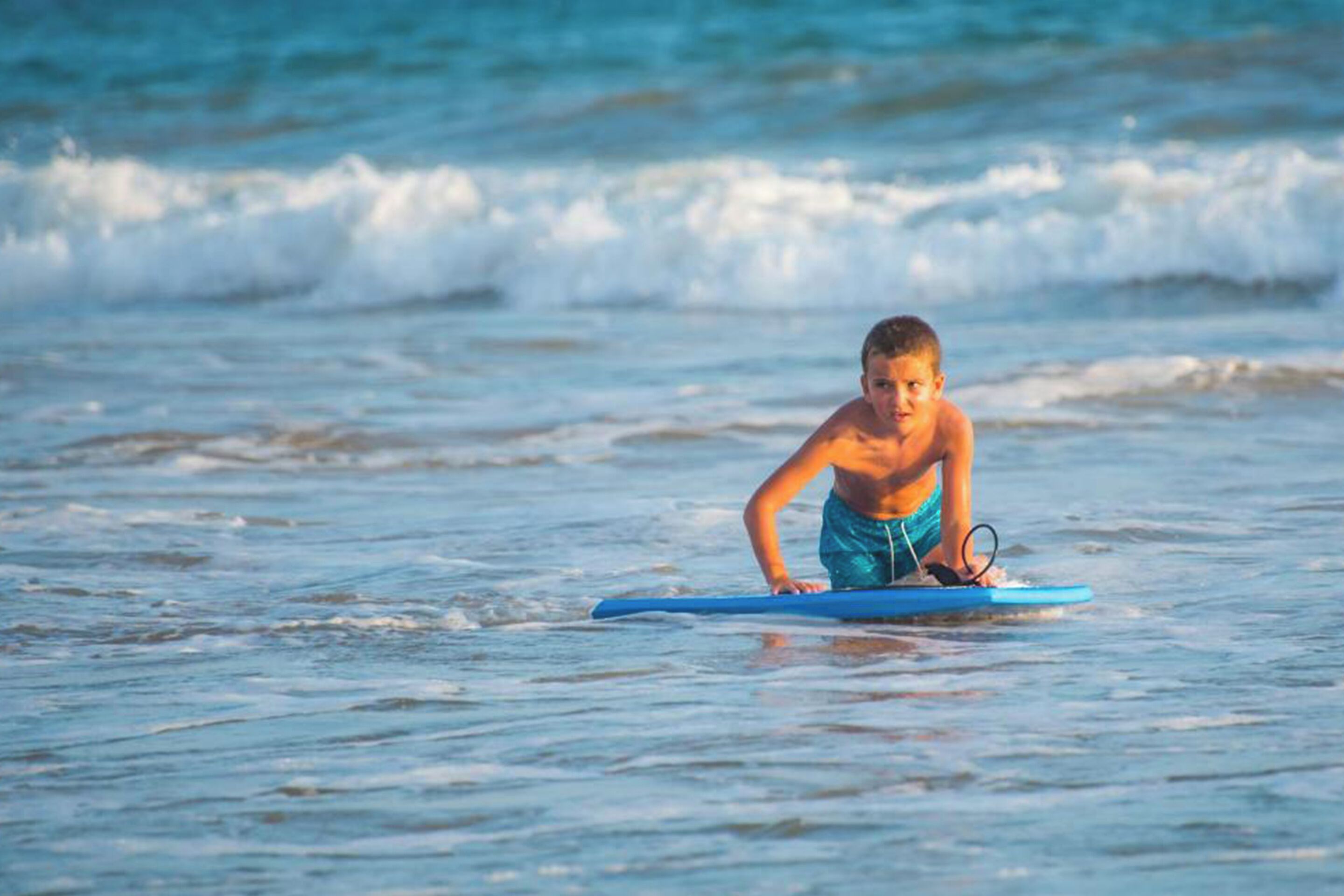 A person on a blue surfboard in the ocean.