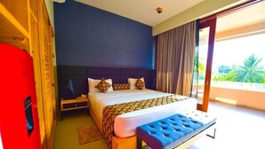 A bedroom with a large bed, a bench, a nightstand, and a view of greenery outside. - Ballena-Mirissa (Mirissa)