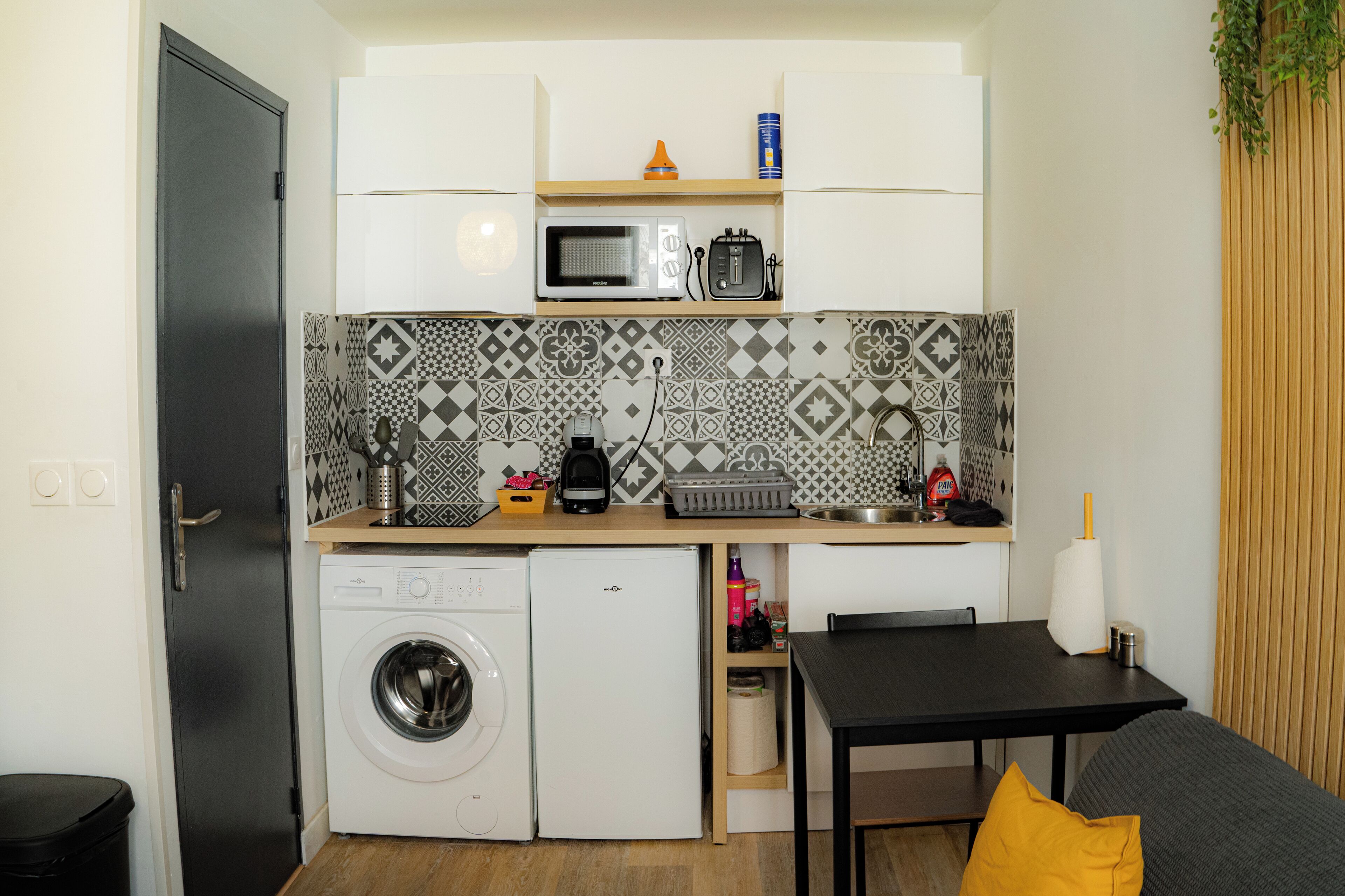 A compact kitchen with a washing machine, a microwave, and a toaster.
