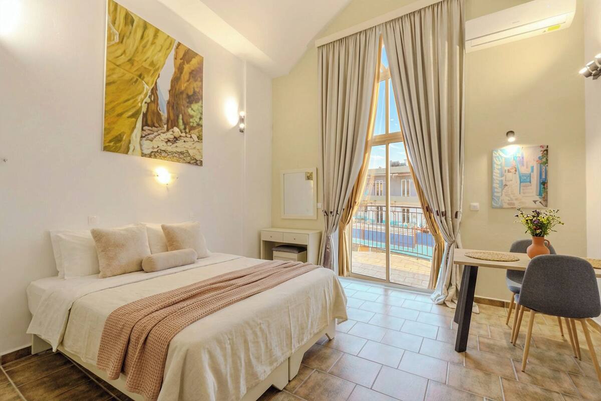 A hotel room with a bed, a desk, and a view of a pool.