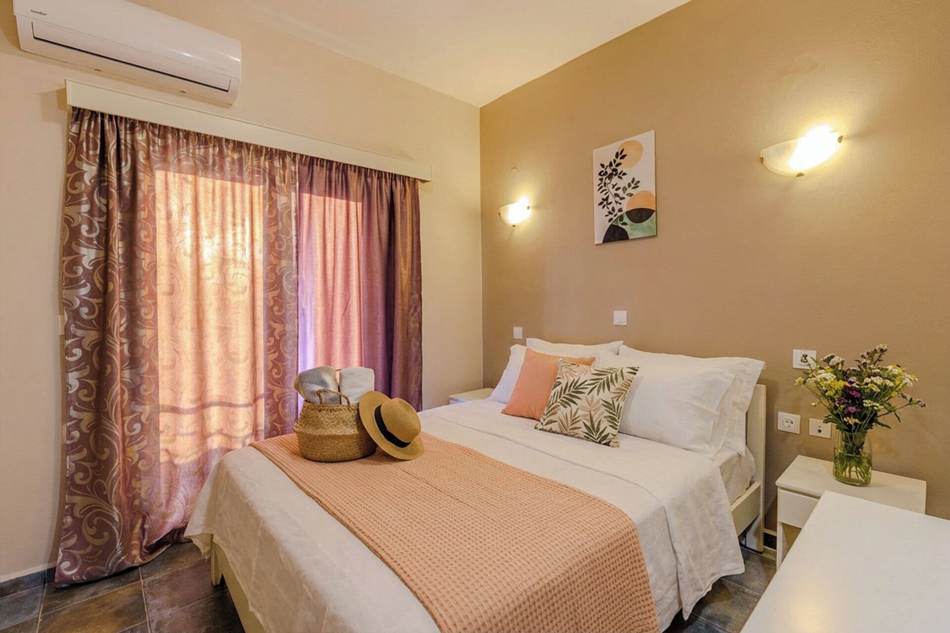 A hotel room with a bed, a bedside table, a wall-mounted air conditioner, and a window with curtains.