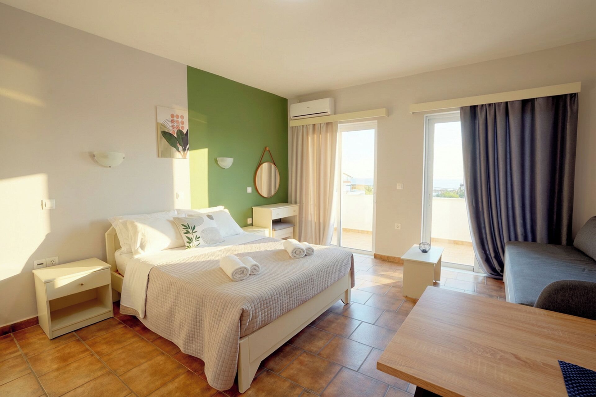 A hotel room with a bed, bedside tables, a desk, and a view of the outdoors.