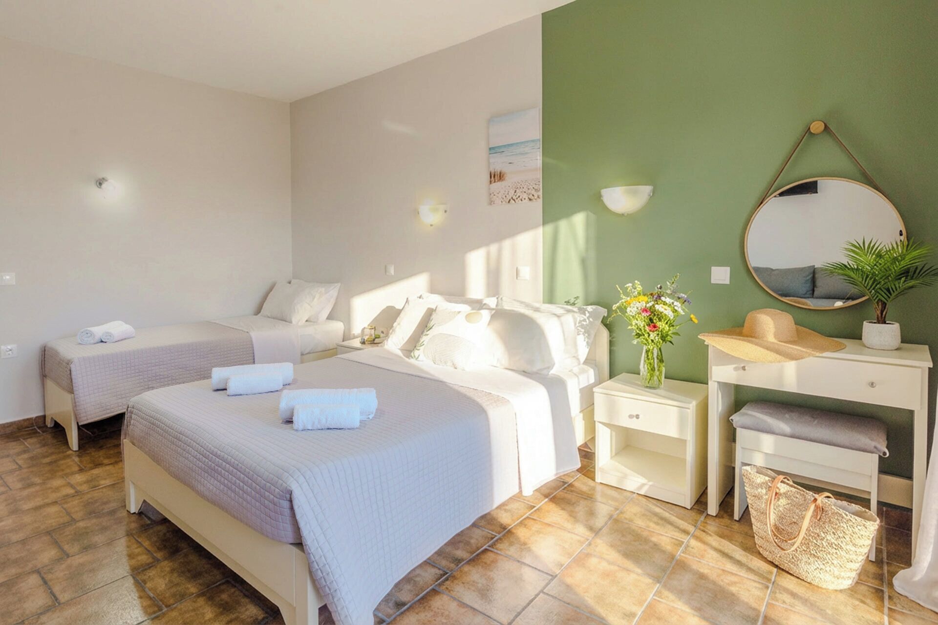 Une chambre d’hôtel avec deux lits, une coiffeuse avec un miroir, une petite table et une plante.