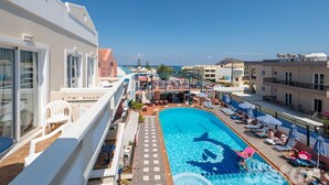 Ein Poolbereich auf dem Dach mit freiem Blick auf das Meer, Liegestühle und eine Poolbar.