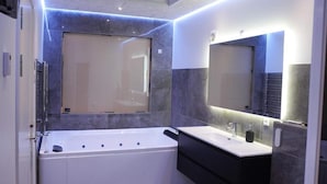 A modern bathroom with a bathtub, a vanity with a mirror, and a shower area. - 4 Star Holiday Home in Aabybro (Aabybro)