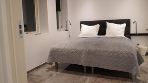 A bedroom with a bed, two bedside lamps, a window, and a wall-mounted light fixture. - 4 Star Holiday Home in Aabybro (Aabybro)