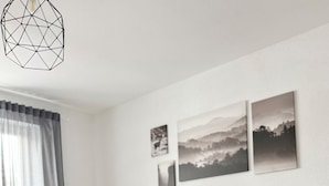 Quarto moderno com estrutura de cama de madeira, roupa de cama cinzenta e três fotografias de paisagens na parede.