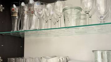 Une vitrine présentant différents types de verres et de tasses, notamment des verres à vin, des gobelets et des mugs, disposés sur des étagères.