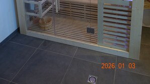 Sauna, jossa on puinen sisustus, lasiovi ja penkki.