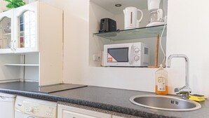 A compact kitchen with a microwave, coffee maker, and a washing machine. - Bright 1BR Apt Perfect for Long Stays (Vienna)