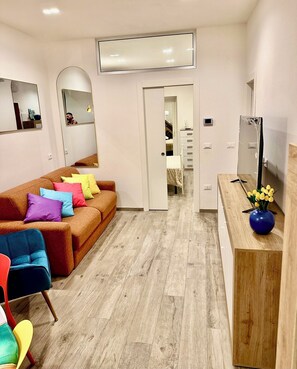A modern living room with a brown sofa, colorful cushions, a wooden coffee table, and a TV on a wooden stand. - L’angolo tranquillo - perfect stay in monterosso historical old town (Monterosso al Mare)