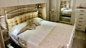 Ein Schlafzimmer mit einem Bett, Nachttischen, einer Kommode und einem Spiegel.