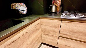 Eine moderne Küche mit Holzausstattung, einer schwarzen Spritzschutzwand und einem Gasherd.