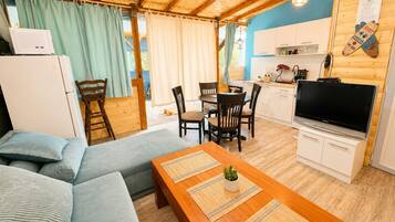 A cozy living area with a sofa, a wooden dining table, and a kitchen area with a TV and cabinets.