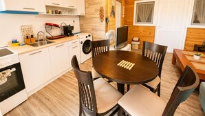 Une cuisine compacte équipée d’un lave-linge, d’une table à manger avec des chaises et d’un téléviseur.
