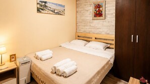 Une chambre d’hôtel avec un plafond en bois, un lit avec du linge de maison blanc, une table de chevet avec une lampe et une armoire.