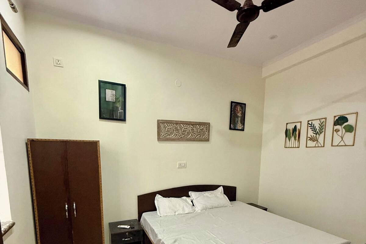 A bedroom with a bed, wardrobe, nightstand, and ceiling fan.