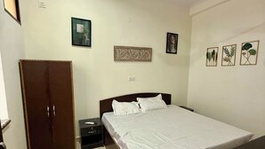 A bedroom with a bed, wardrobe, nightstand, and ceiling fan. - Saroj Serenity inn (Rishikesh)