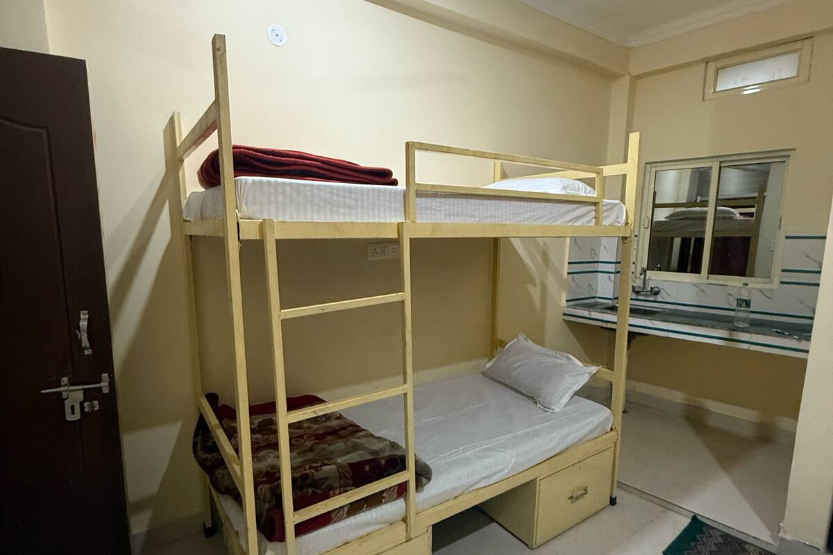 A bunk bed room with a door, a mirror, and a window.