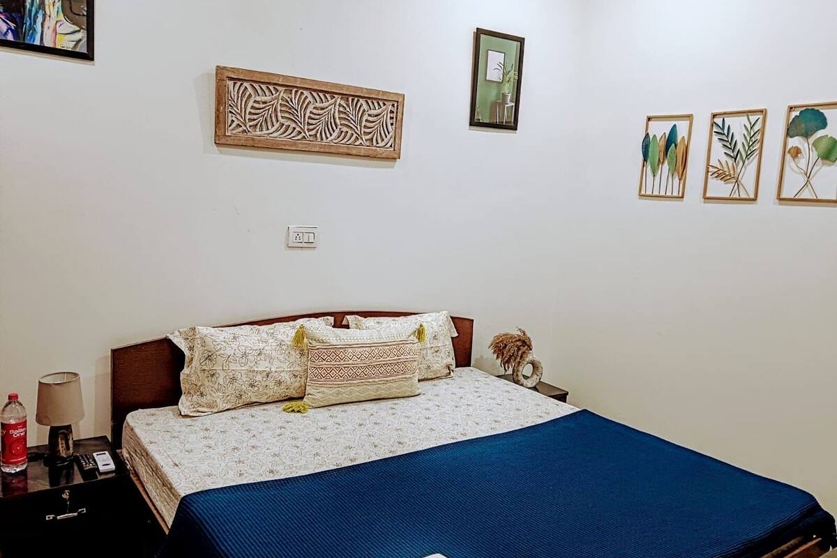 A bedroom with a bed, a nightstand, a lamp, and wall art.