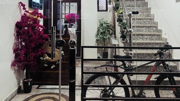 A staircase with a metal railing, a bicycle, and a potted plant. - Saroj Serenity inn (Rishikesh)
