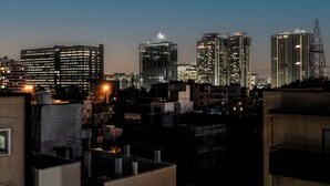 A cityscape at dusk with illuminated high-rise buildings and a clear sky. - Hotel Royal Manyaa (Bengaluru)