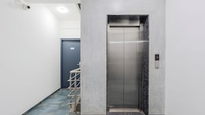 An elevator with a marble finish, a blue door, and a metal handrail. - Hotel Royal Manyaa (Bengaluru)