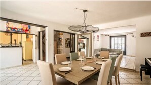 Uma sala de jantar com uma mesa de madeira posta para quatro pessoas, rodeada por cadeiras.