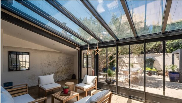 Um quarto iluminado pelo sol, com teto de vidro, mobiliário de madeira e vista para o jardim.