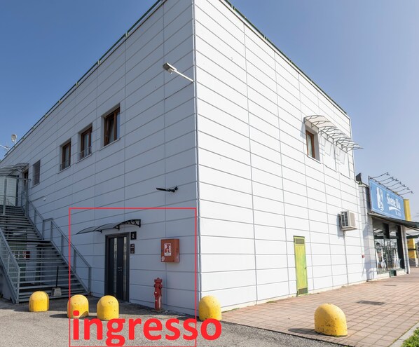 A building with a white facade, a fire hydrant, and yellow bollards. - SMART ROOMS Foresteria (Viadana)