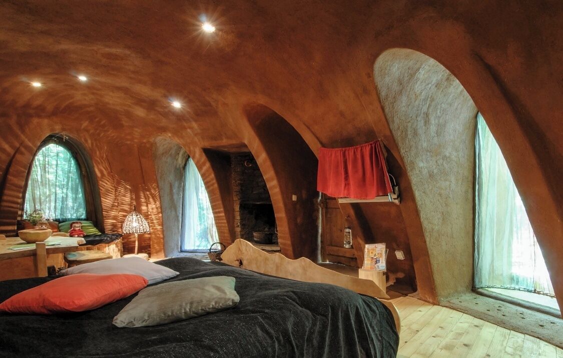 Ein gemütliches Schlafzimmer im Dachgeschoss mit einem Bett, einem kleinen Tisch und einem Fenster mit Blick auf Grünflächen.