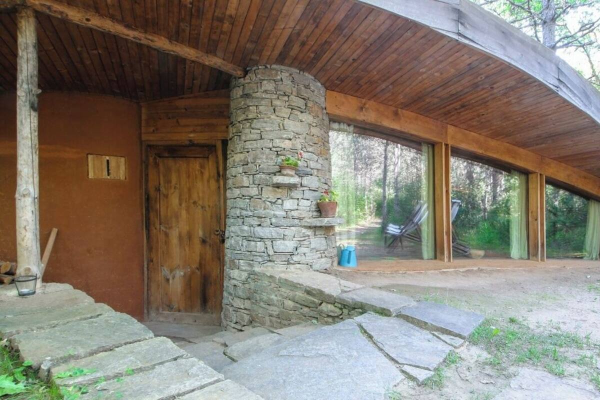 Un chalet rustique avec un pilier en pierre, une porte en bois et de grandes fenêtres.