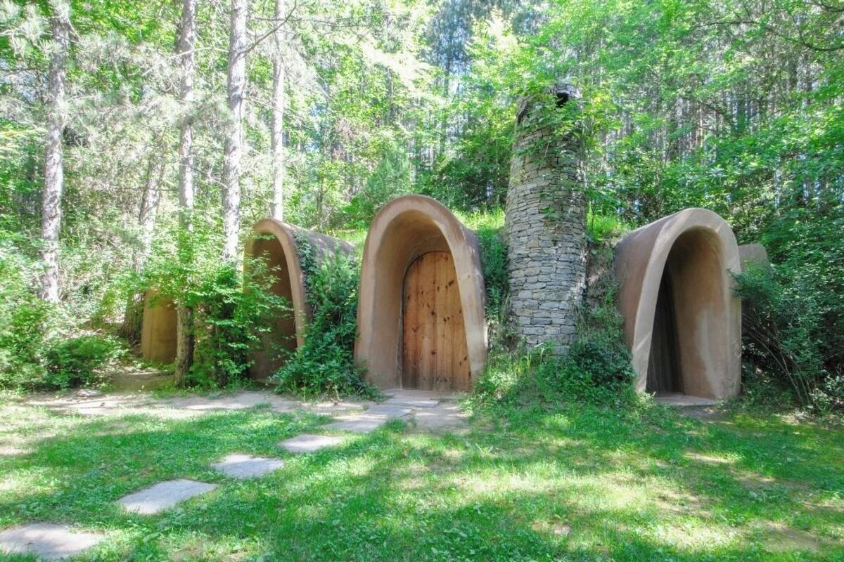 Une zone boisée comprenant trois structures en forme d’arche, faites de bois, qui pourraient faire partie d’un bâtiment de style rustique ou naturel.