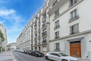 A row of parked cars along a street lined with multi-story buildings with balconies and a large wooden door. - We Parisian * Invalides* Cozy Home (Paris)