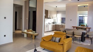 Un salon moderne comprenant un canapé, une table à manger avec des chaises, un coin cuisine et un grand miroir.