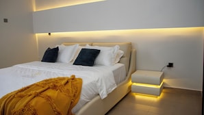 Une chambre à coucher moderne avec un lit, une table de chevet et une lampe fixée au mur.