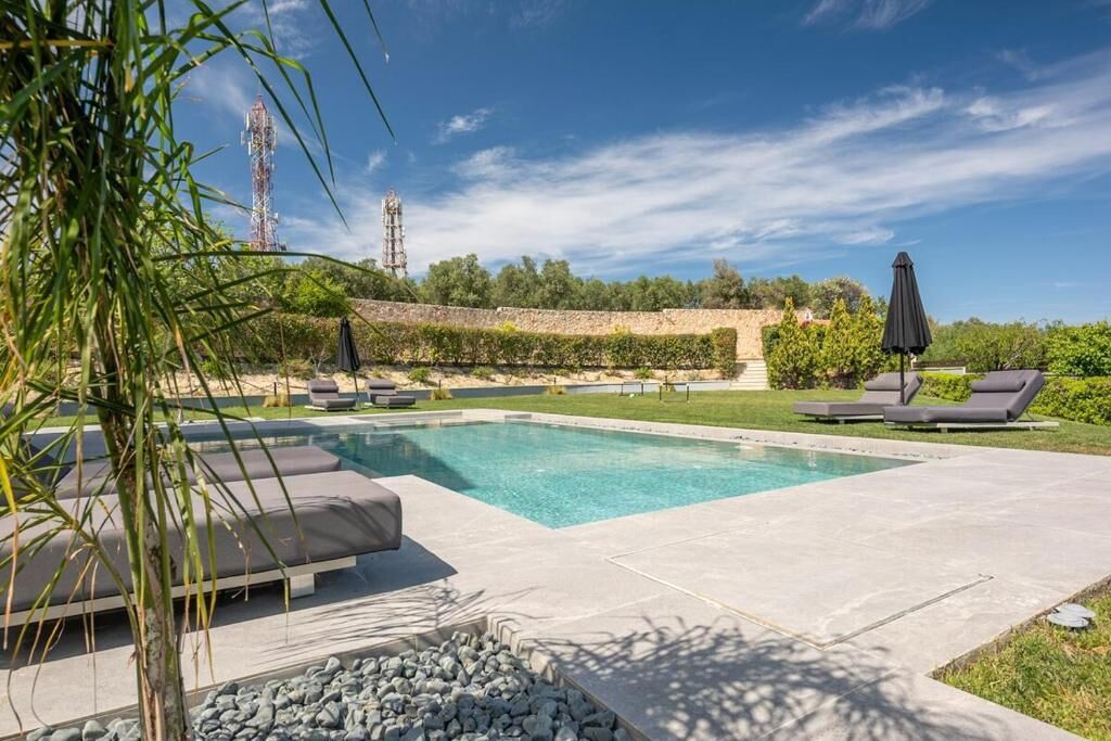 Een buitenzwembad, ligstoelen bij het zwembad