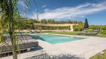 Een buitenzwembad, ligstoelen bij het zwembad