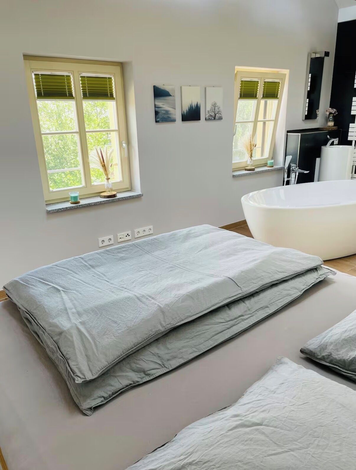 Ein modernes Badezimmer mit freistehender Badewanne, einem großen Fenster mit Jalousien und einem wandmontierten Spiegel.