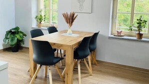 A dining area with a wooden table, black chairs, and pendant lights.