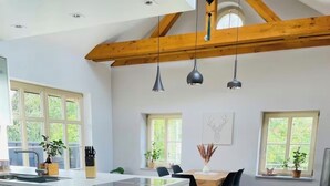 A modern kitchen with a central island, wooden beams, and pendant lighting.
