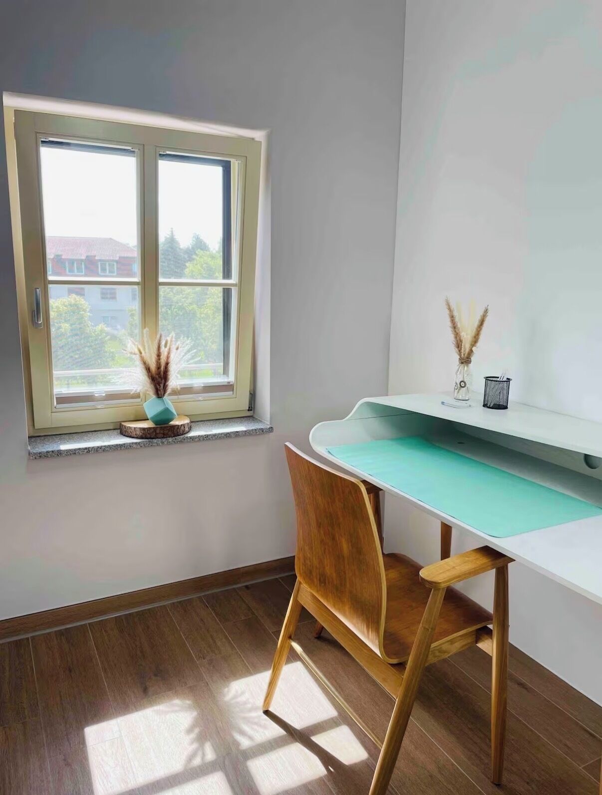 Une pièce d’angle avec une fenêtre, un bureau, une chaise et une petite plante.
