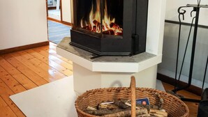 A fireplace with a basket of firewood in front. - 6 Person Holiday Home in Hunnebostrand (Kungshamn)