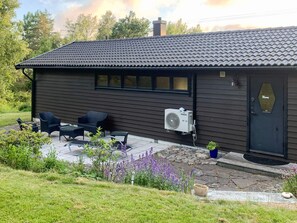 A house with a dark brown exterior, a tiled roof, and a front porch with outdoor furniture. - 6 Person Holiday Home in Hunnebostrand (Kungshamn)